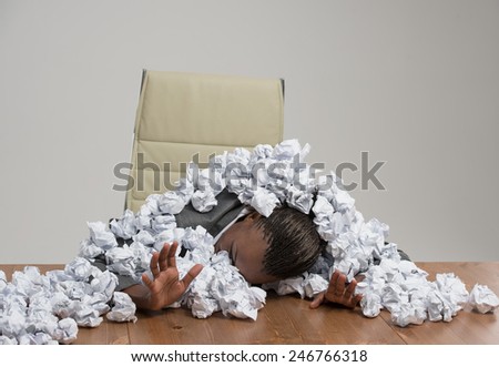 Young african business woman covered in crumpled papers against gray background