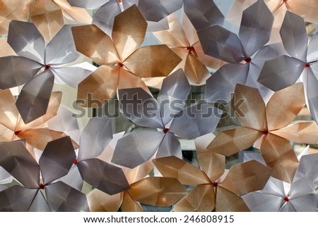 Blue and orange paper flowers glued on glass. The sun shines through the paper and makes the image a beautiful abstract background.