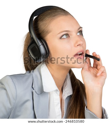 Businesswoman in headset, with her fingers on microphone boom, looking ahead and upward, her mouth open. Isolated over white background