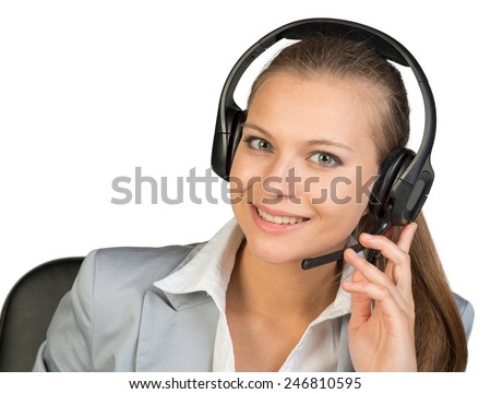 Businesswoman in headset, with her fingers on microphone boom, her head tilted slightly to the side, looking at camera, smiling. Isolated over white background