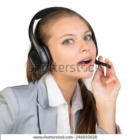 Businesswoman in headset, with her fingers on microphone boom, looking at camera, her mouth open. Isolated over white background