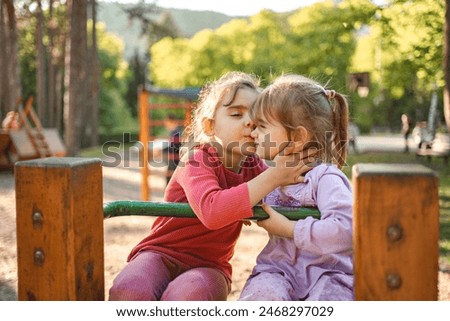 Girl kisses her younger sister on the playground