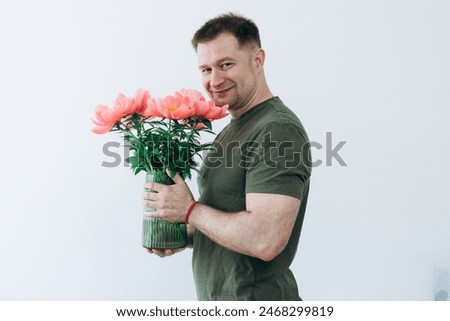 Guy holds vase with peonies in his hands