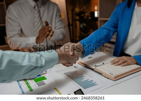 they are doing handshake in the office because they just signed the contract to be a partner of business, these businesspeople have commitment to merge their business for make more income, handshake