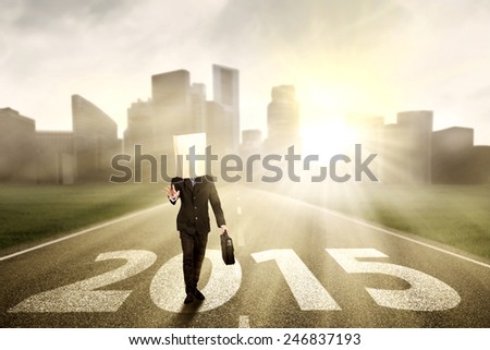 Male entrepreneur with blindfold on his head walking on the road with numbers 2015 