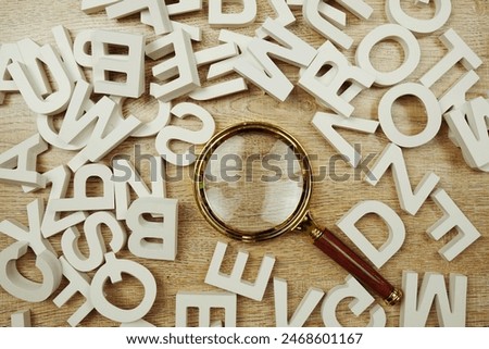 Top view random wooden alphabet letters with magnifying glass on wooden background