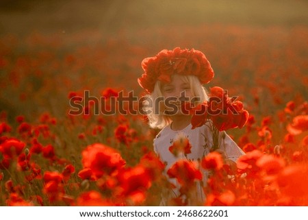 A young girl is standing in a field of red poppies