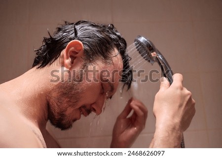 A man takes a refreshing shower, enjoying the water streaming down from the showerhead, feeling rejuvenated.