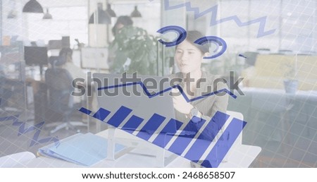 Image of financial data processing over asian businesswoman having image call at office. Business, finances, communication and digital interface concept digitally generated image.