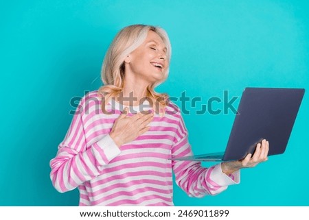 Photo of good mood woman with blond hair wear striped sweatshirt holding laptop palm on chest laugh isolated on blue color background