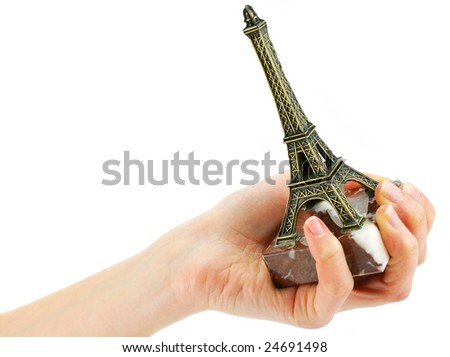 Woman's hand holding statuette of Eiffel Tower isolated on a white background