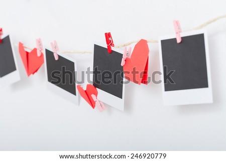 Deco for love day. Empty instant photo and origami hearts hanging on clothesline