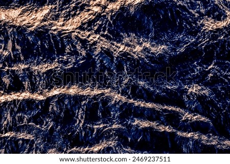 The image is of a body of water with waves and ripples. The water appears to be dark blue in color, and the waves are creating a sense of movement and energy