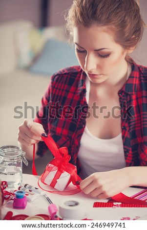 Woman creating gift at home with paper and gouache