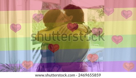 Image of heart emojis and rainbow flag over caucasian female couple embracing. Lgbtq, love, romance and celebration concept digitally generated image.