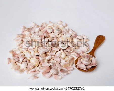 Garlic cloves and a wooden spoon are placed on a white background. It's a very beautiful picture.