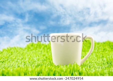 White coffee cup on green grass with blue sky,Spring Season