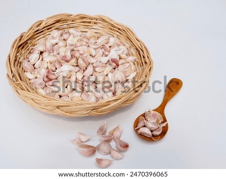 Garlic cloves are placed in a wicker basket on a white background. It's a very beautiful picture.