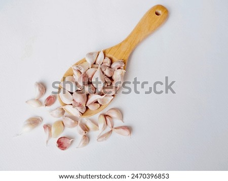 Garlic cloves are placed in a wooden spoon on a white background. It's a very beautiful picture.