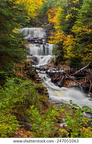 Sable Falls, a waterfall in Upper Peninsula Michigan's Pictured Rocks National Lakeshore, is surrounded by fall color and evergreen trees.