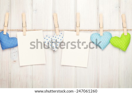Two photo frames and valentines day toy hearts over white wooden background