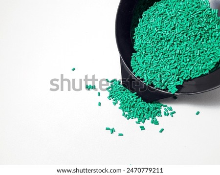 Turquoise masterbatch granule spill out of a black cup onto a white background.  Color pigment carrier polymers in the plastics industry