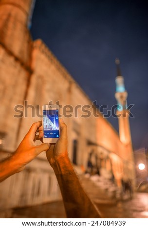 Tourist photographing Blue Mosque with smartphone at night, Istanbul, hands detail.