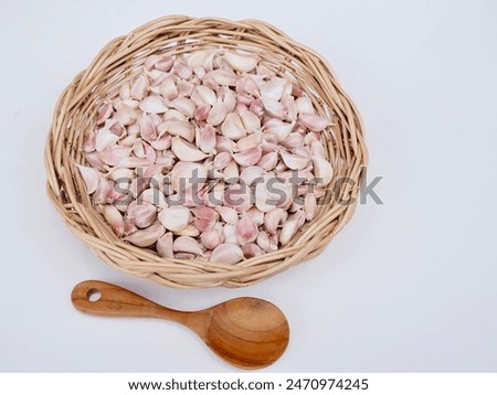 Garlic cloves are placed in a wicker basket on a white background. It's a very beautiful picture.