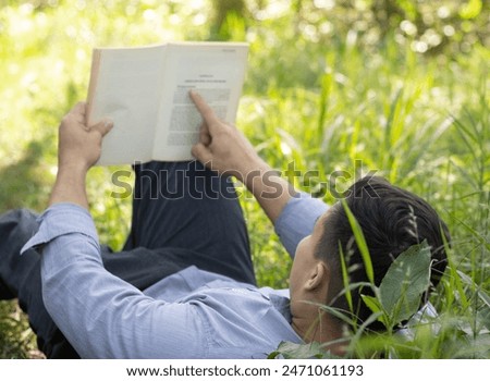 young latin man reading a book in nature with his back turned in high resolution and high quality. concept read HD