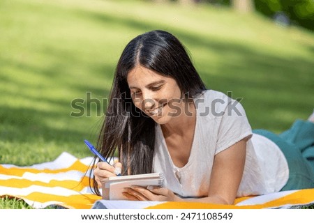 beautiful young happy writer is inspired by nature to write ideas for her future love novel in her notebook