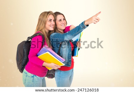 Student women pointing to the lateral over ocher background  