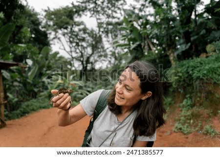 Curious tourist holding a chamaleon in an african natural reserve while trekking. Materuni, Tanzania