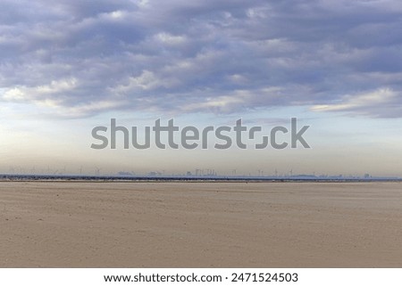 Panoramic picture over the beach of Ouddorp in Holland with the silhouette of the port of Rotterdam on the horizon in the evening