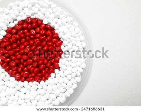 Red and white masterbatch granules in a cup, isolated on white background.  Color pigment carrier polymer for the plastics industry