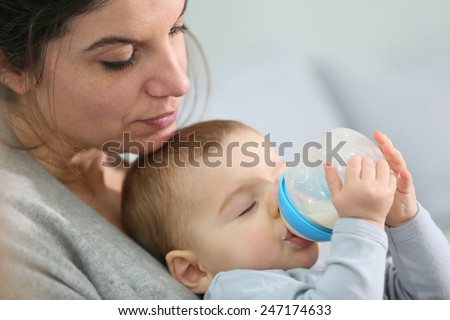 Mother and baby boy holding baby bottle