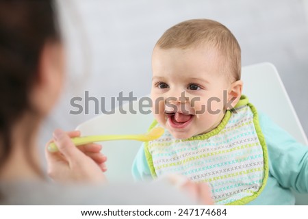 Mother giving fruit sauce to baby boy Royalty-Free Stock Photo #247174684