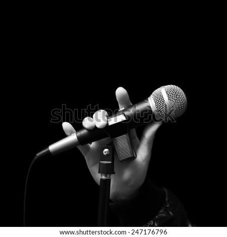 singer right hand holding dynamic microphone, bw filter & isolated on black ( hand sign mean love ) concept = love to sing