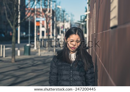 Young beautiful Chinese girl with long hair posing in the city streets