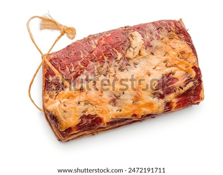 A single piece of cured meat is photographed on a white background. The meat is dried and covered with caraway seeds, giving it a rustic and savory appearance. 