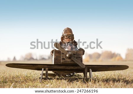 Young Aviator sits in his makeshift toy airplane on airport parking Royalty-Free Stock Photo #247266196