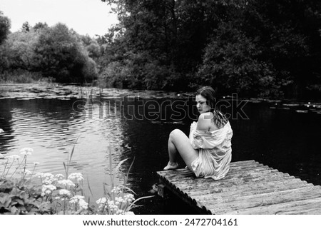 A young beautiful girl swims in a pond. Black and white photo.