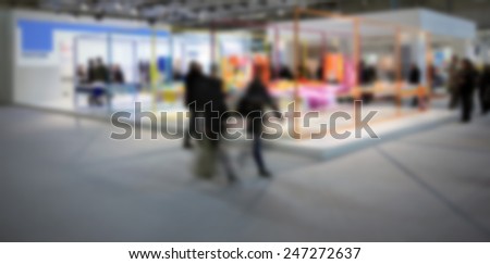 People visit a trade show. Intentionally blurred post production background.