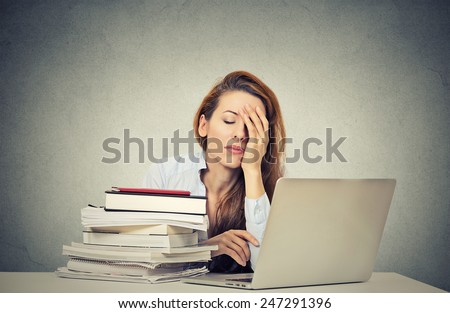Too much work tired sleepy young woman sitting at her desk with books in front of laptop computer isolated grey wall office background. Busy schedule in college, workplace, sleep deprivation concept Royalty-Free Stock Photo #247291396