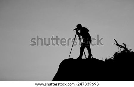 Silhouette of a photographer who shooting a sunset on the mountains in black and white