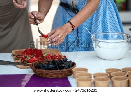 A woman adds strawberries to a dessert, preparing to top it off with whipped cream. 