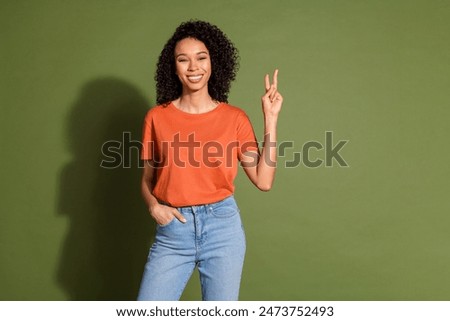 Photo portrait of attractive young woman show v-sign dressed stylish orange clothes isolated on khaki color background