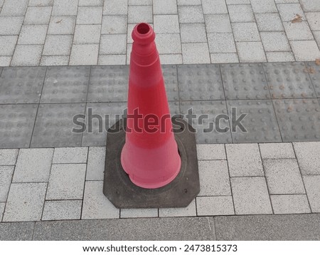 Safety Cones or traffic cone, cone with orange color on gray asphalt and Interlocks. 
Red safety cones used for Warning and caution. 