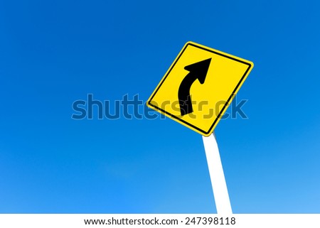 Yellow traffic right curve sign on blue sky background.