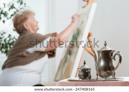 Active senior woman using easel during painting
