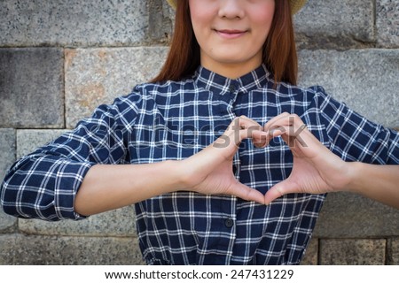 smile woman holds heart shape on own. Love emotion (focus shirt)